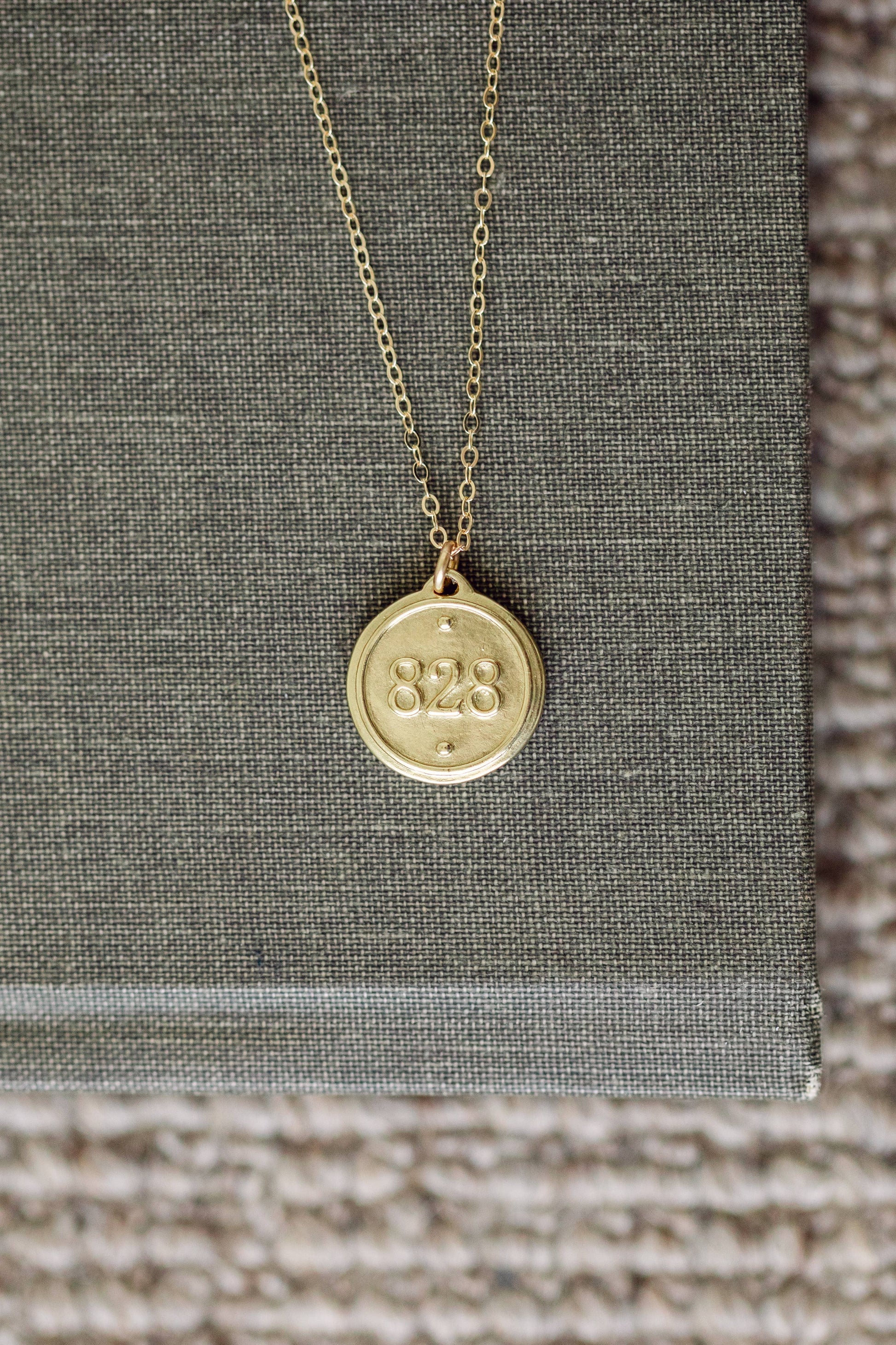 Gold necklace with a round pendant on a textured surface