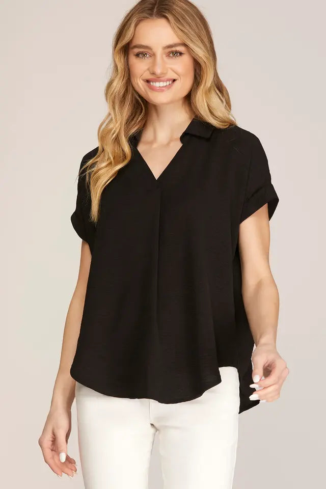 Woman wearing a black short-sleeve blouse against a plain background