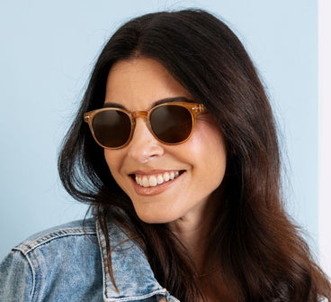 Woman wearing sunglasses and a denim jacket against a light blue background