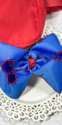 Blue hair bow with red accents on a white lace doily