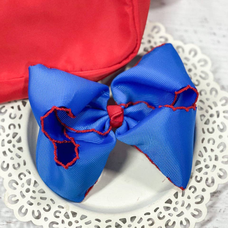 Blue hair bow with red accents on a white lace doily