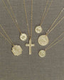 Gold necklaces with various pendants on a gray fabric background