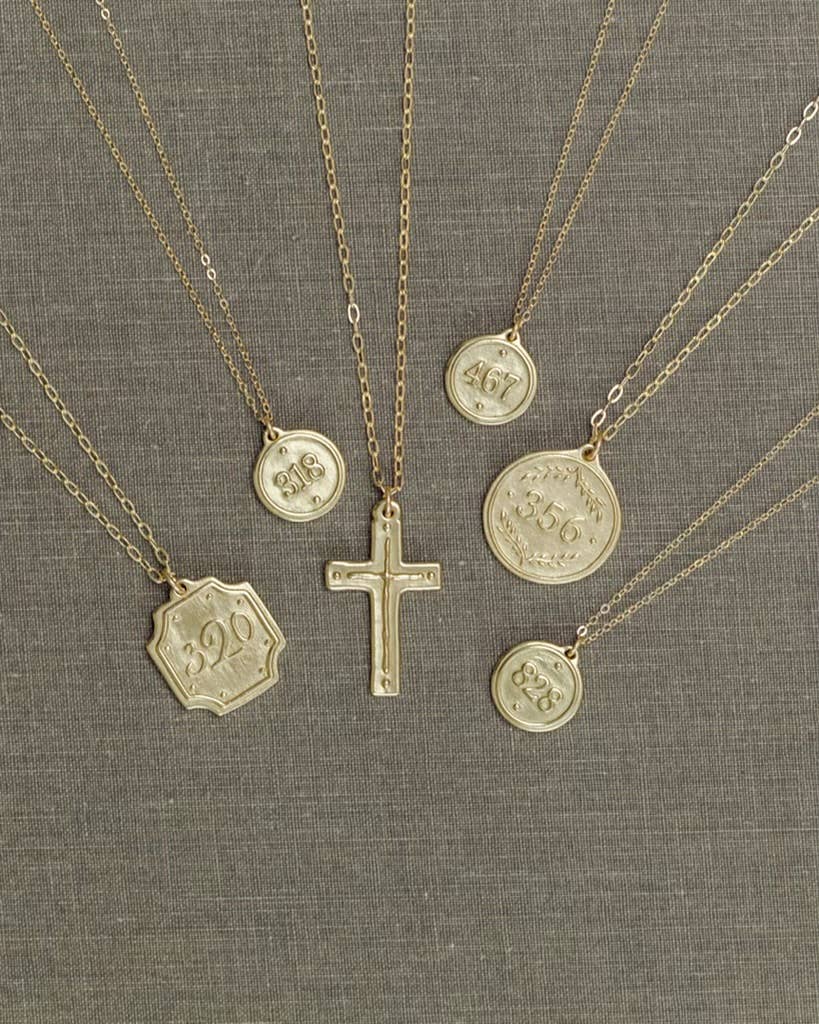 Gold necklaces with various pendants on a gray fabric background