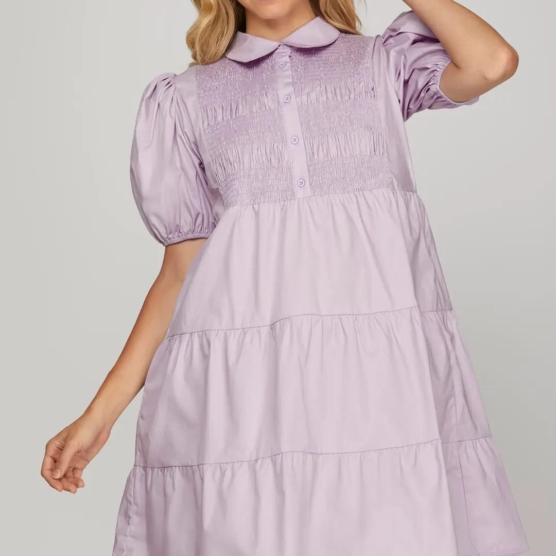 Woman wearing a lilac dress with a plain background