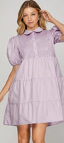 Woman wearing a lilac dress with a plain background