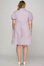 Woman wearing a light purple dress with puff sleeves on a plain background