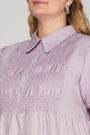 Close-up of a person wearing a light purple dress with a collar.