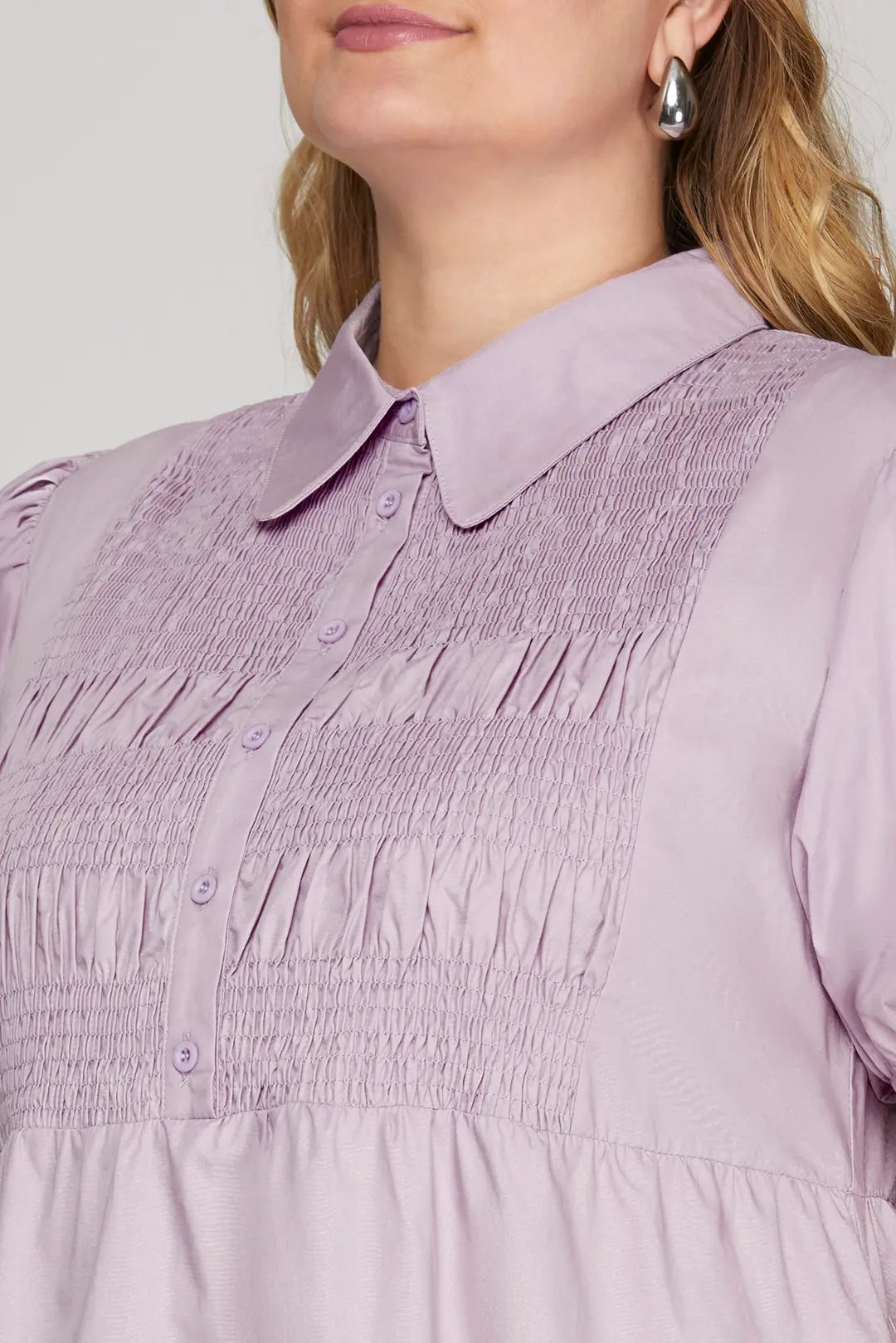 Close-up of a person wearing a light purple dress with a collar.