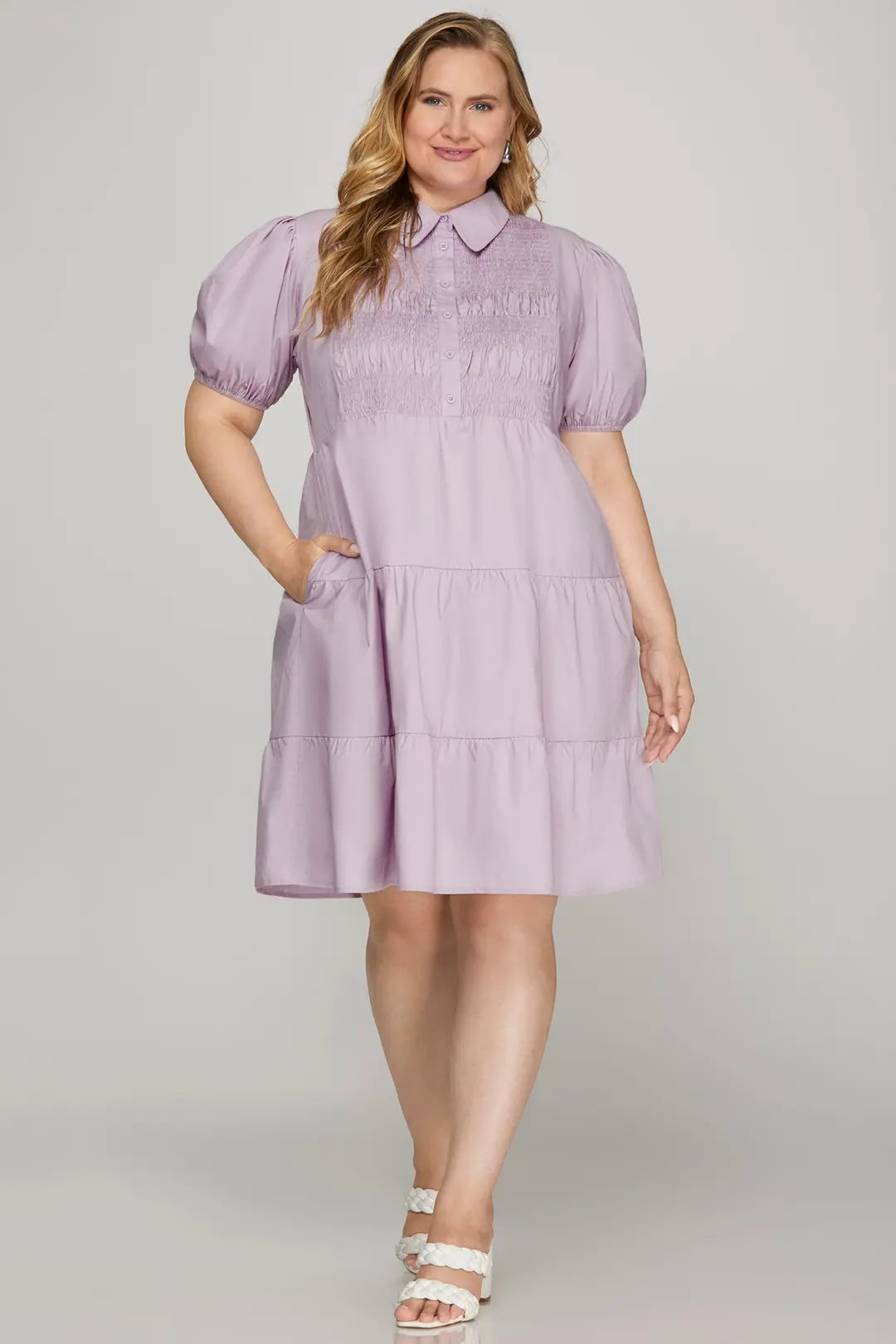 Woman wearing a purple dress with puffed sleeves on a plain background