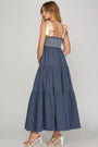 Woman wearing a blue tiered dress with a white background