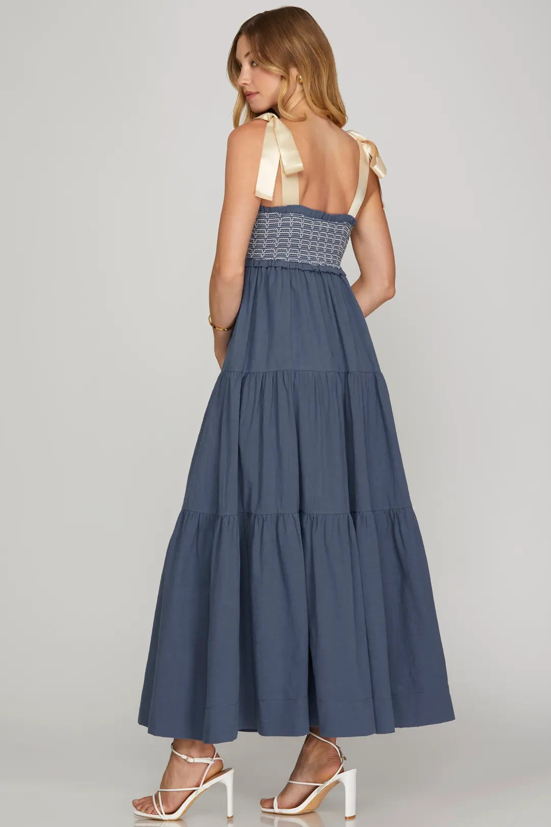 Woman wearing a blue tiered dress with a white background