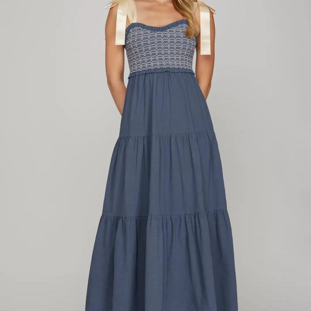 Woman wearing a blue dress with a white top on a gray background