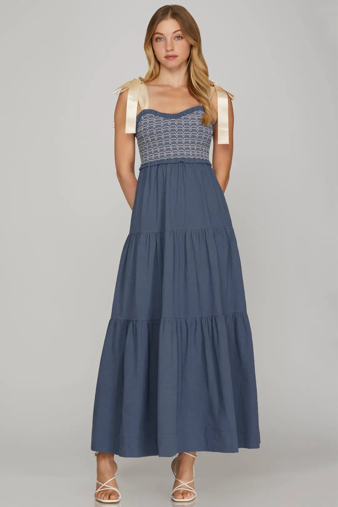 Woman wearing a blue dress with a white top on a gray background