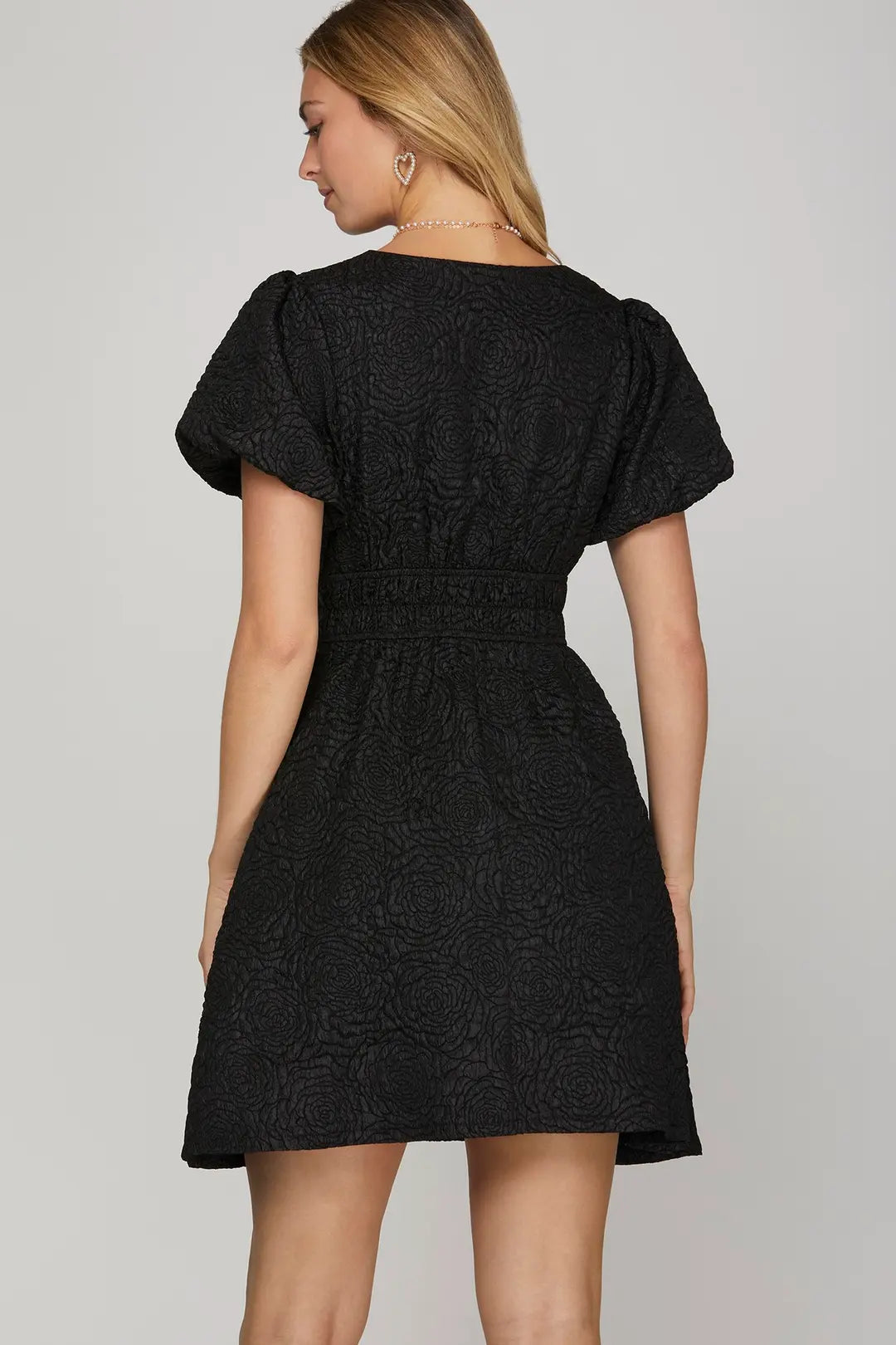 Black dress worn by a model on a plain background