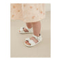White sandals worn by a child on a neutral background