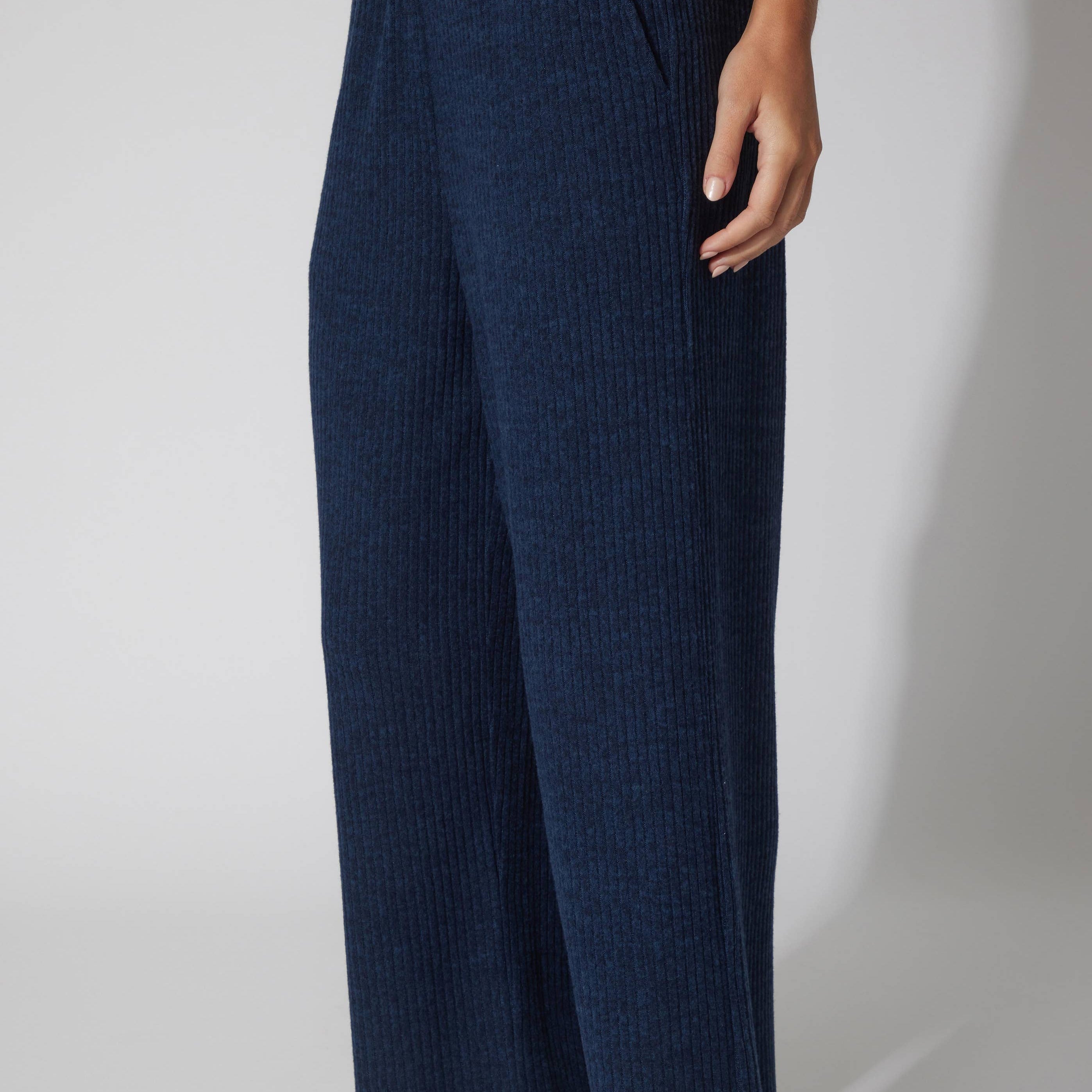 Navy blue textured pants worn by a person on a white background