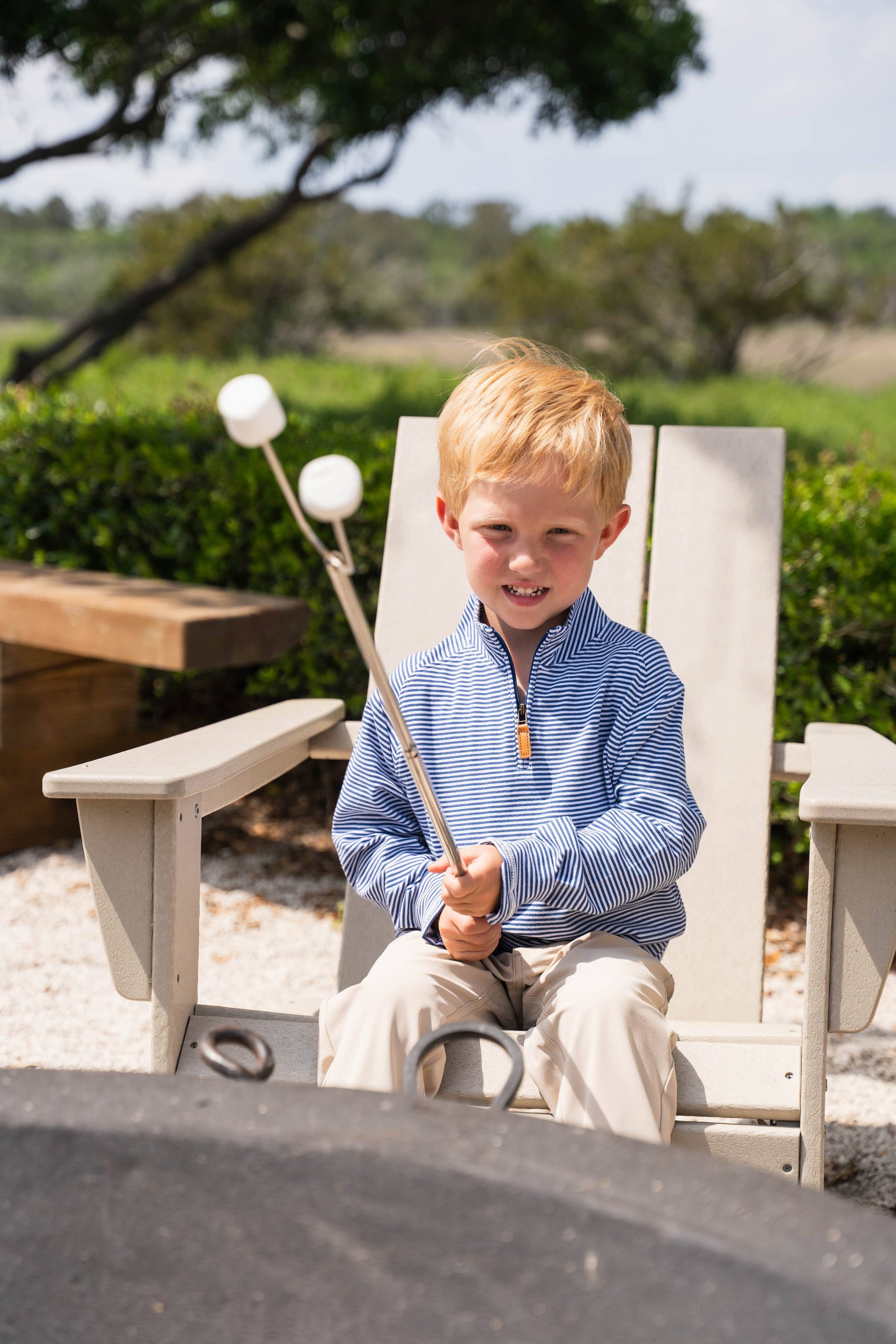 Young boy roasting marshmallows over a fire pit outdoors