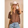 Woman wearing a brown polka dot blouse and white cowboy hat against a beige background