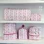 Set of pink and white patterned bags on a shelf with 'TRVLP' branding.