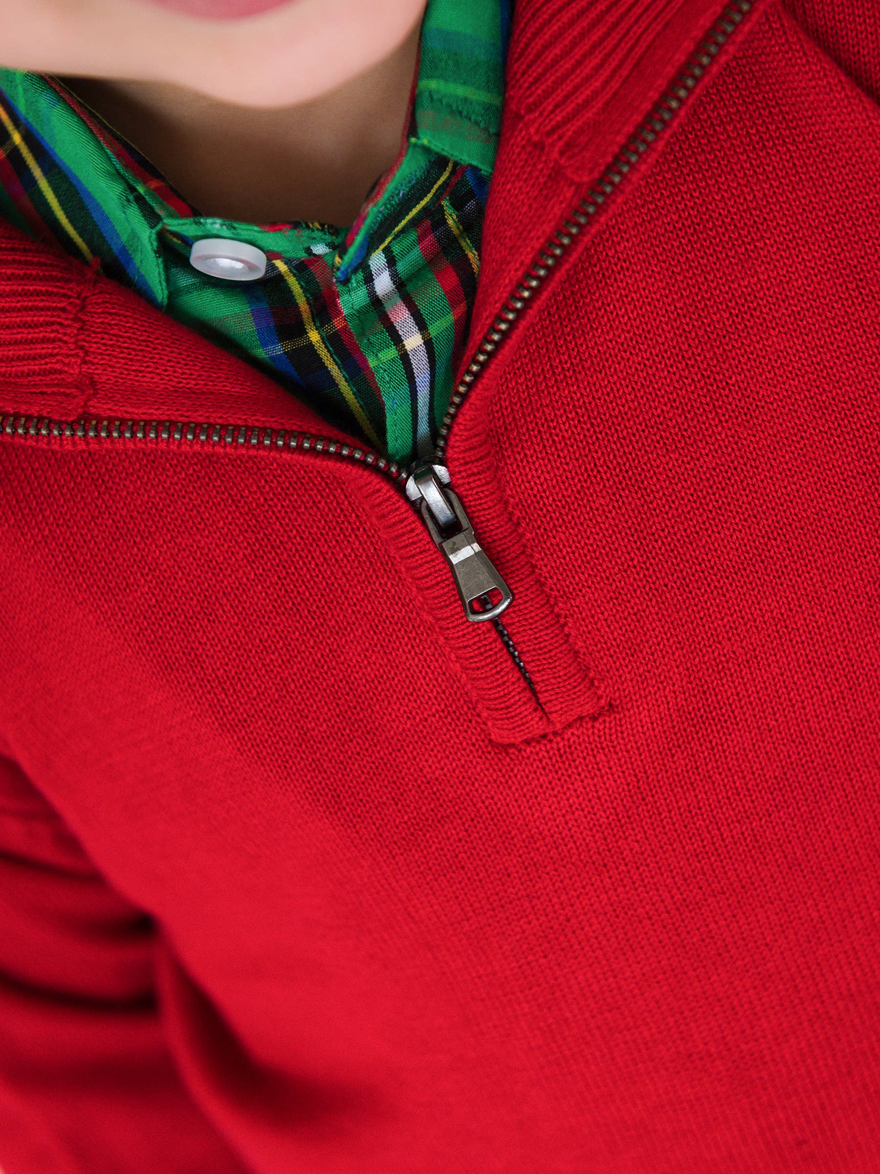Close-up of a red sweater with a zipper and plaid collar.