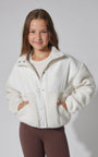 Young girl wearing a white fleece jacket against a plain background