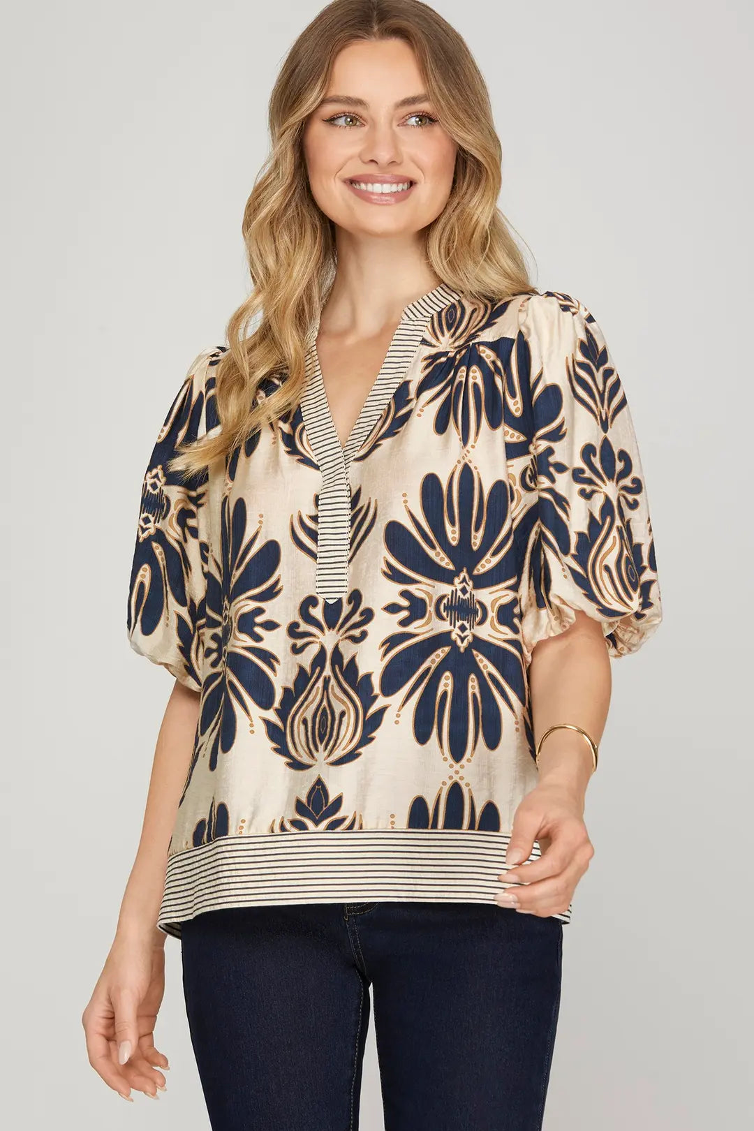 Woman wearing a patterned blue and cream blouse with a plain background
