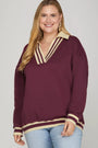 Woman wearing a burgundy sweater with cream accents on a plain background