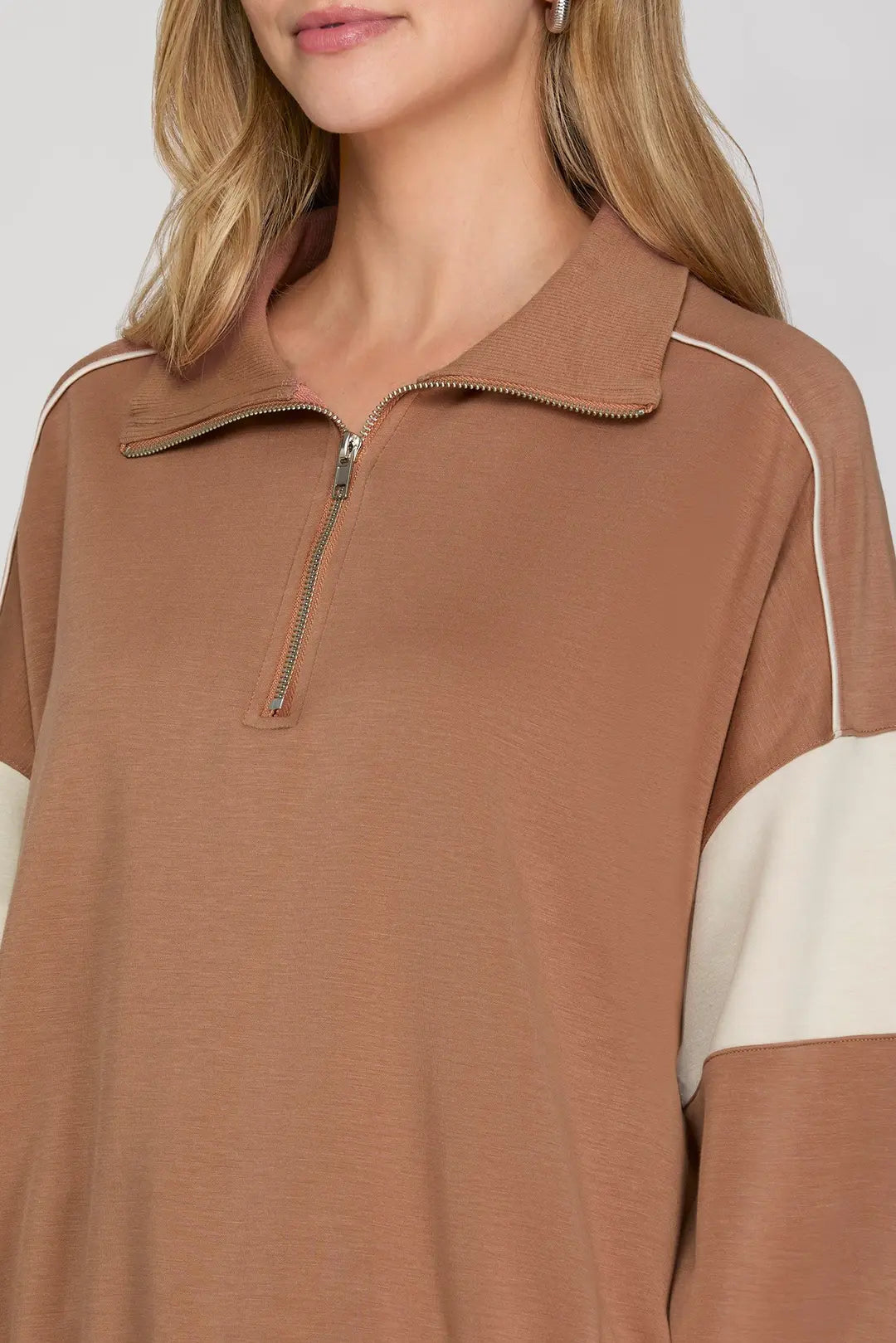 Brown and beige long-sleeve top with a zipper detail on a white background