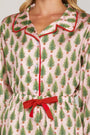 Close-up of a pink pajama top with green tree pattern and red trim.