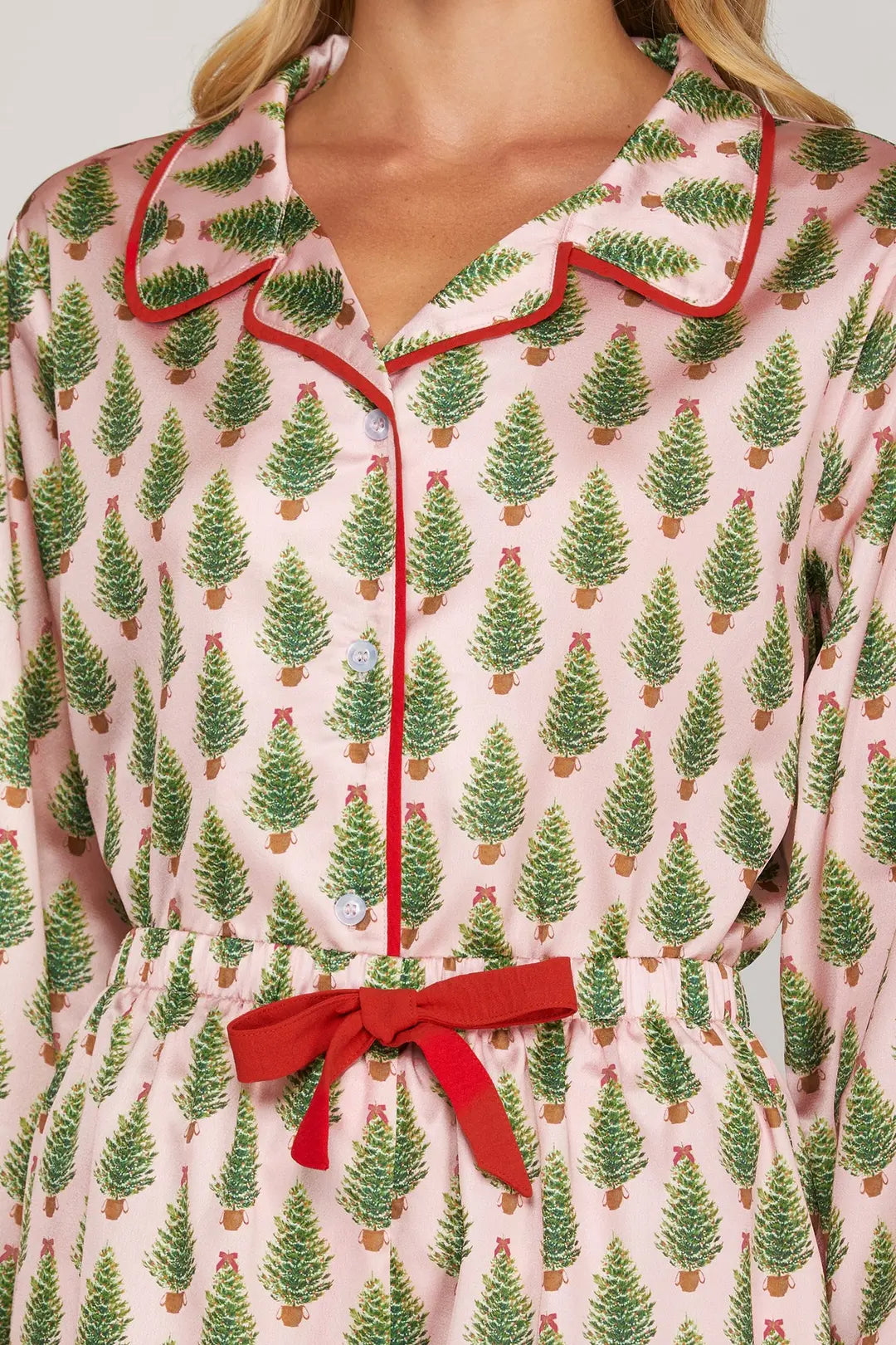 Close-up of a pink pajama top with green tree pattern and red trim.