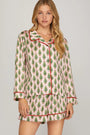 Woman wearing a festive pajama set with Christmas tree pattern on a plain background
