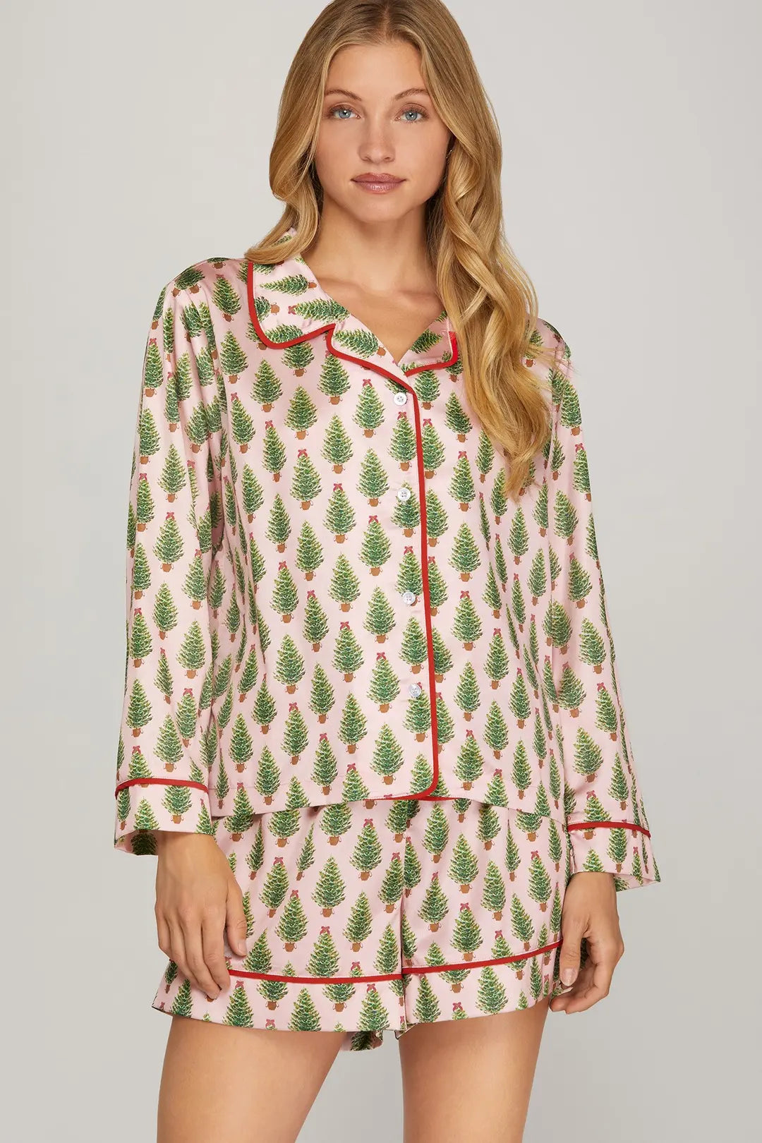 Woman wearing a festive pajama set with Christmas tree pattern on a plain background