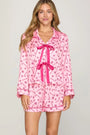 Women wearing long sleeve pink pajama top that ties in the front with matching shorts with dark pink candy cane and peppermint design