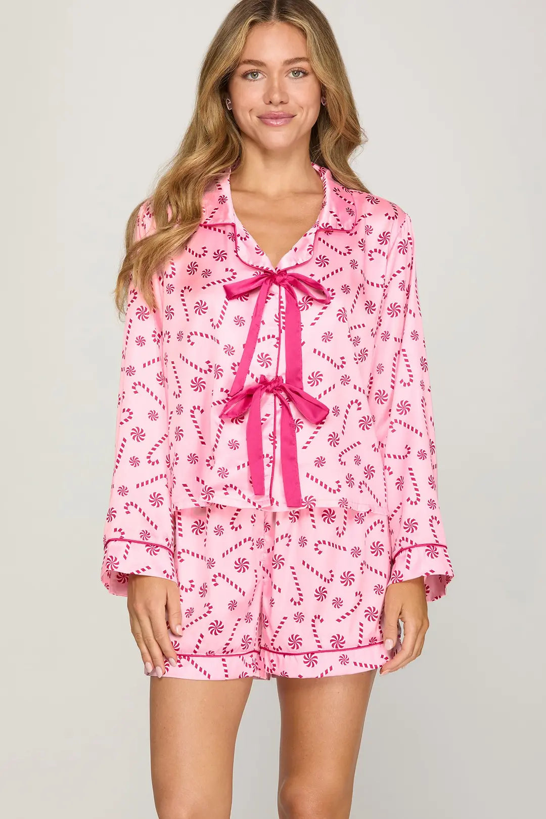 Women wearing long sleeve pink pajama top that ties in the front with matching shorts with dark pink candy cane and peppermint design