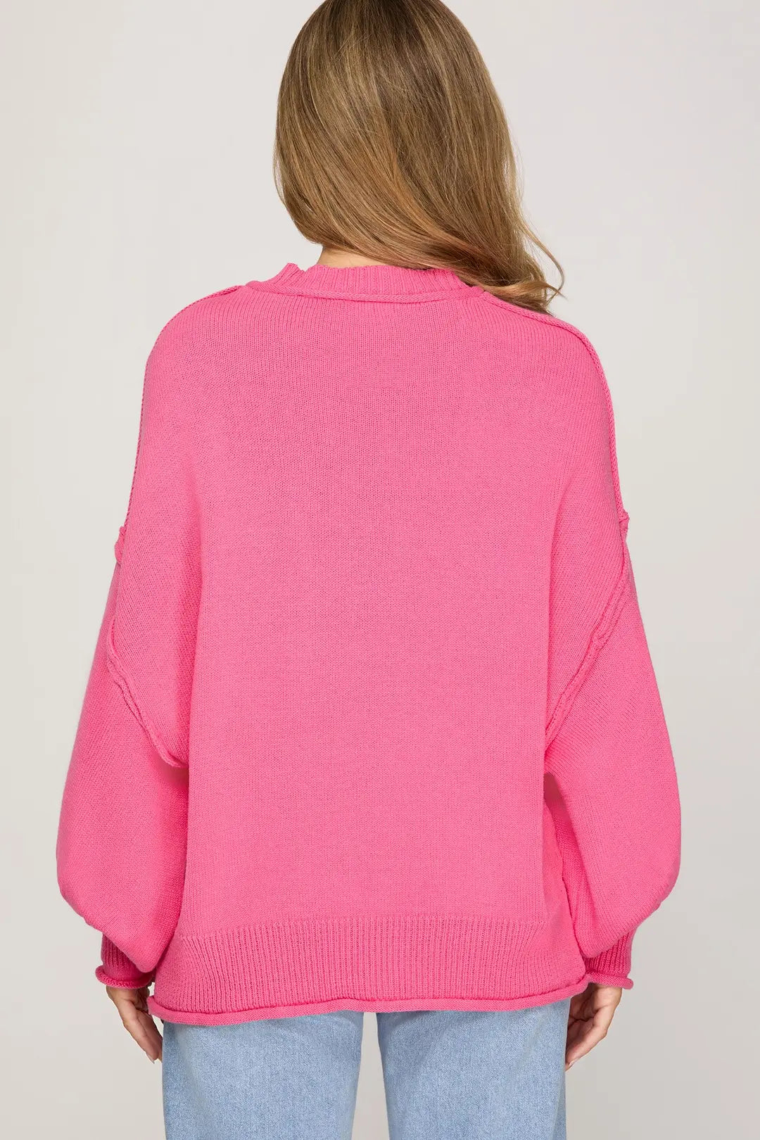 Person wearing a bright pink sweater on a plain background