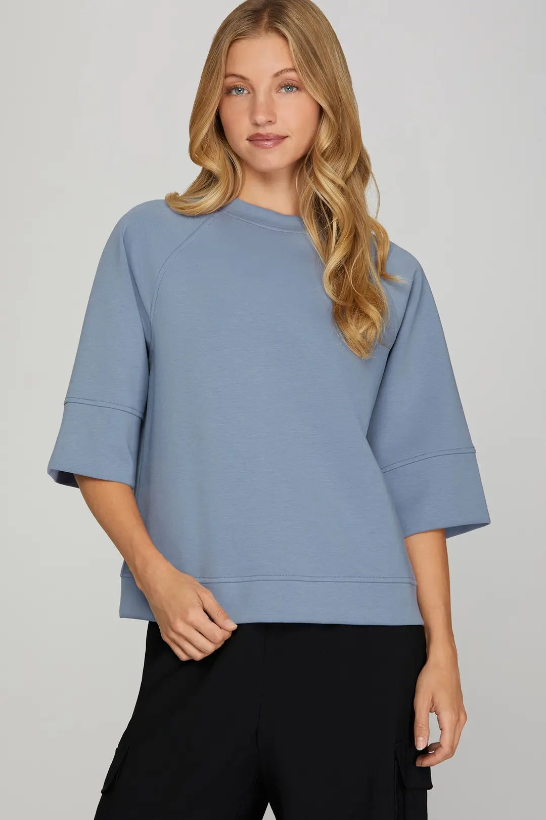 Woman wearing a light blue sweater against a gray background