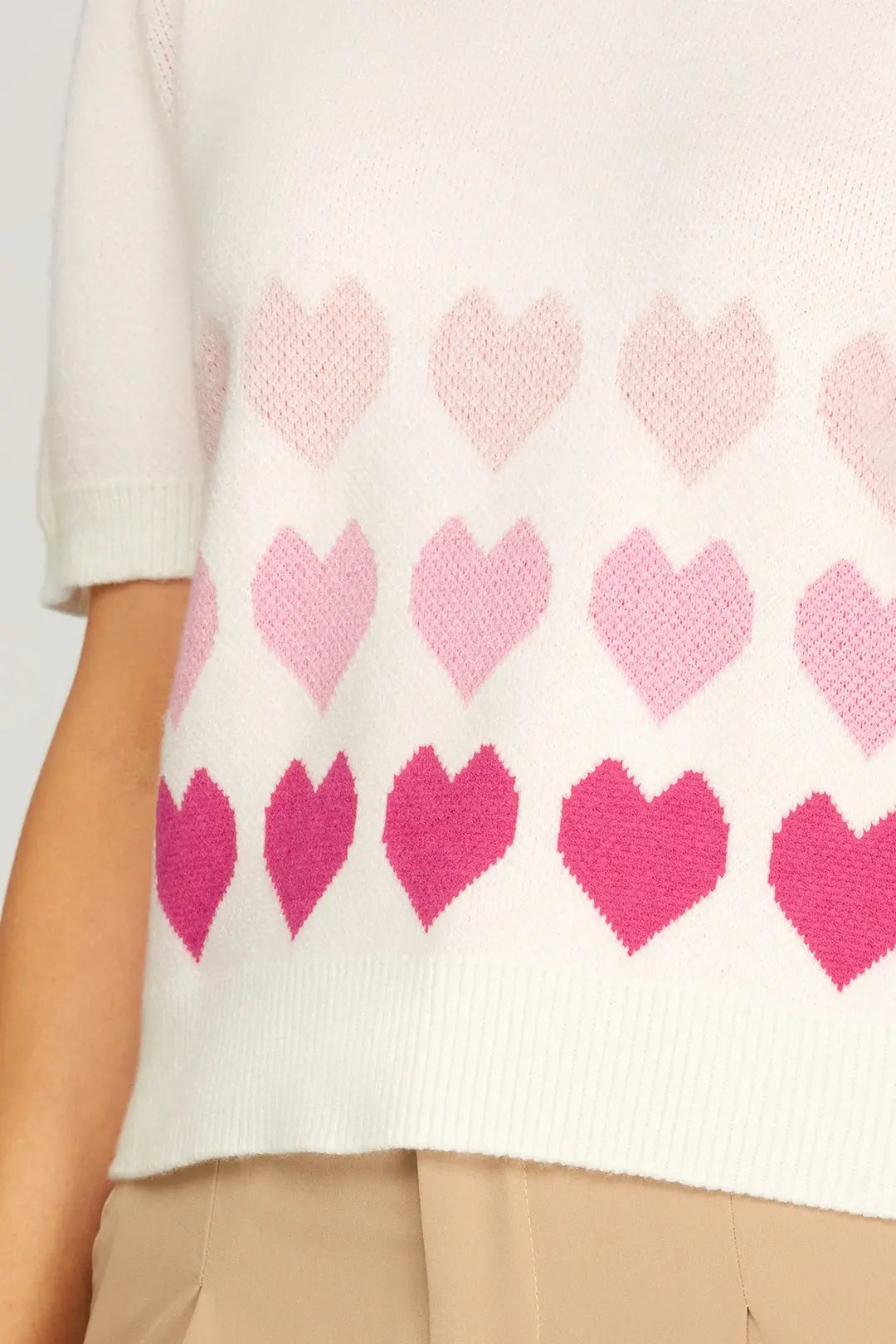 Close-up of a sweater with pink heart pattern on a white background