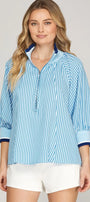 Woman wearing a blue striped shirt with white shorts on a plain background