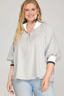 Woman wearing a striped shirt with a collar and rolled-up sleeves on a gray background