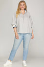 Woman wearing a striped shirt and light blue jeans on a plain background