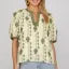 Woman wearing a yellow floral blouse with a blurred background