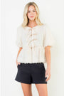 Woman wearing a white lace top and black shorts on a white background
