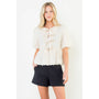 Woman wearing a white lace top and black shorts on a white background