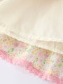 Close-up of a floral fabric with pink lace trim on a white background
