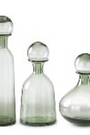 Set of three green glass decanters with different shapes on a white background