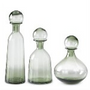 Set of three green glass decanters with different shapes on a white background