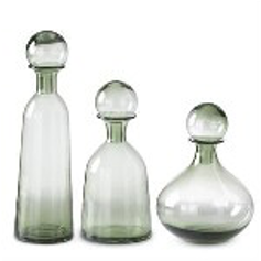 Set of three green glass decanters with different shapes on a white background