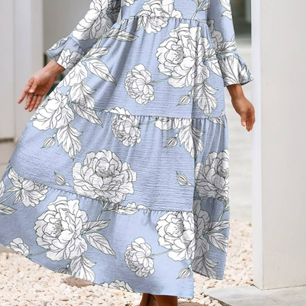 Woman wearing a blue floral dress standing on pebbles with a white archway in the background