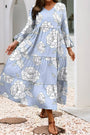 Woman wearing a blue floral dress standing on pebbles with a white archway in the background