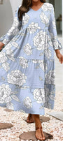 Woman wearing a blue floral dress standing on pebbles with a white archway in the background